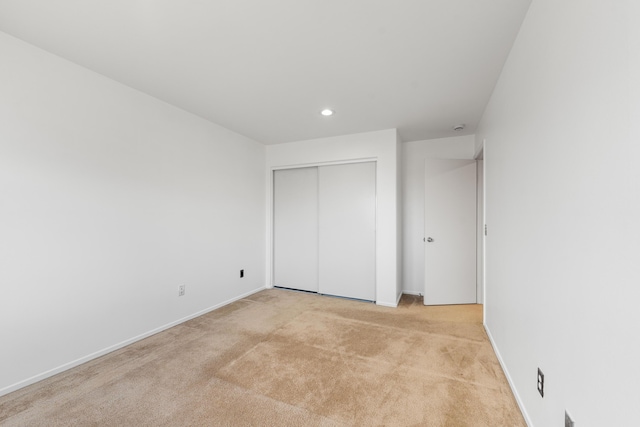 unfurnished bedroom with light carpet and a closet