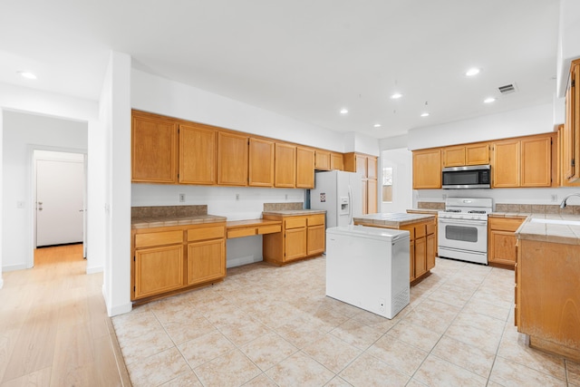 kitchen featuring white appliances, a kitchen island, and sink