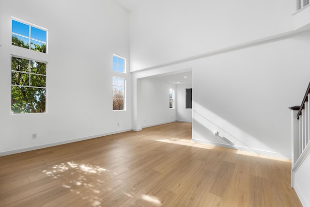 unfurnished living room featuring light hardwood / wood-style floors and a high ceiling