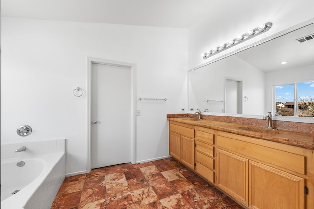 bathroom with vanity and tiled tub