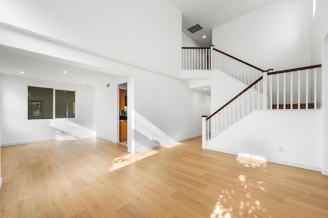 interior space featuring a towering ceiling and light wood-type flooring