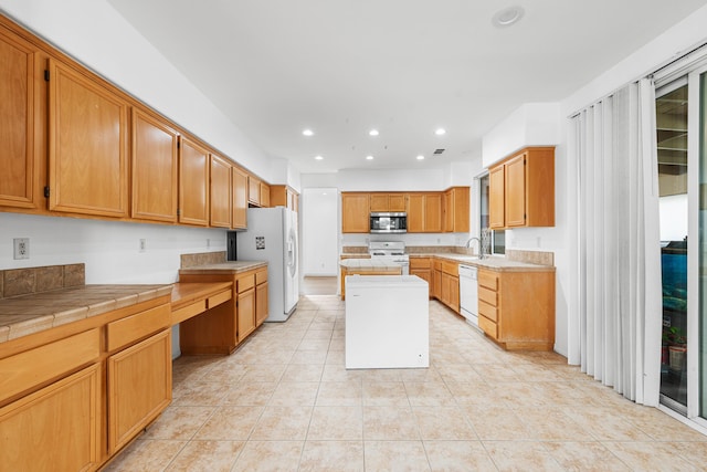 kitchen featuring tile counters, a center island, sink, white appliances, and light tile patterned floors