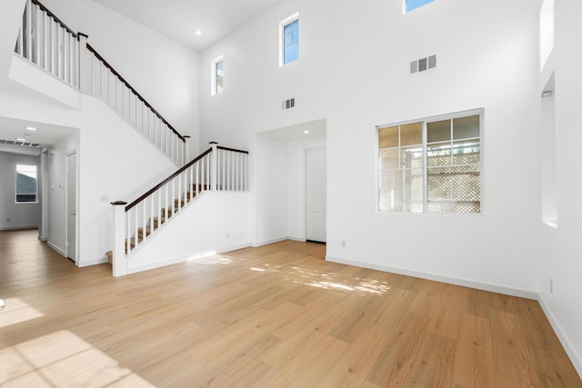 unfurnished living room featuring light hardwood / wood-style flooring and a high ceiling