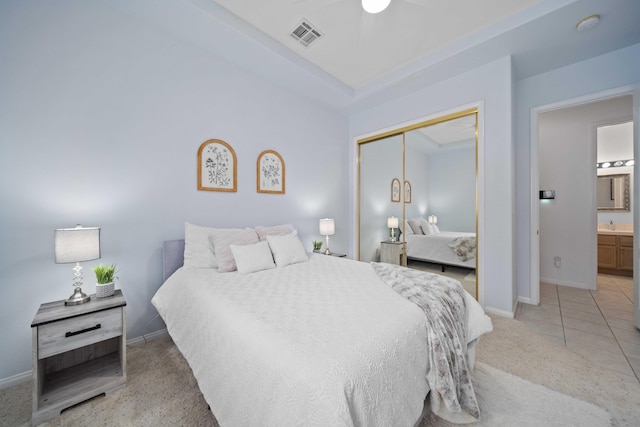 bedroom with light tile patterned floors, baseboards, visible vents, a closet, and light carpet