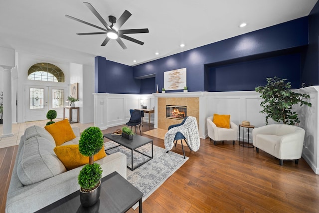 living room with decorative columns, a decorative wall, wood finished floors, and a tile fireplace