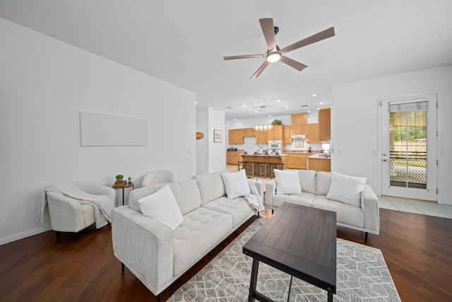 living room featuring ceiling fan with notable chandelier, recessed lighting, wood finished floors, and baseboards