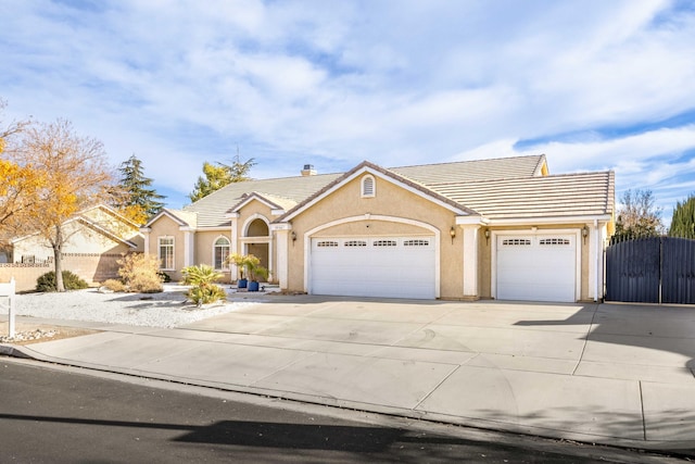 view of front of home with a gate, stucco siding, an attached garage, and a tiled roof