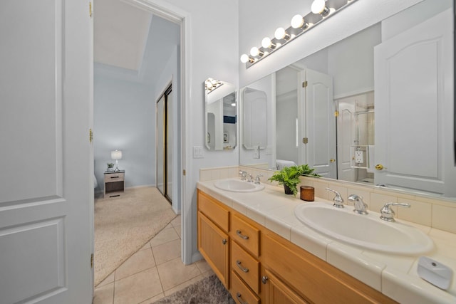 bathroom with tile patterned flooring, double vanity, a shower with shower door, and a sink