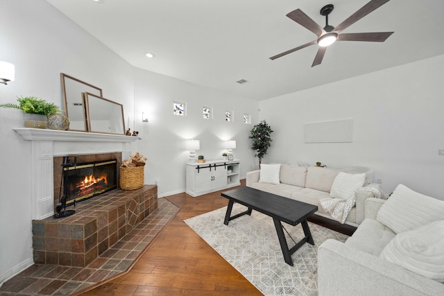 living room with hardwood / wood-style floors, baseboards, visible vents, ceiling fan, and a brick fireplace