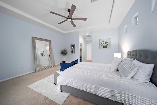 bedroom featuring a raised ceiling, a ceiling fan, baseboards, and light carpet