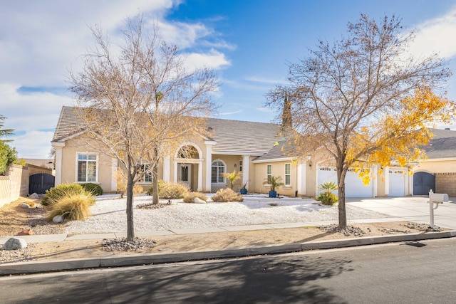 view of front of house featuring stucco siding, an attached garage, concrete driveway, and fence