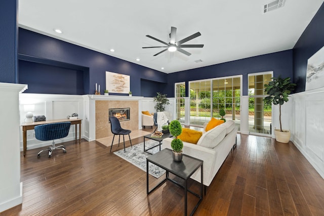 living room with visible vents, a fireplace, a decorative wall, and wood-type flooring