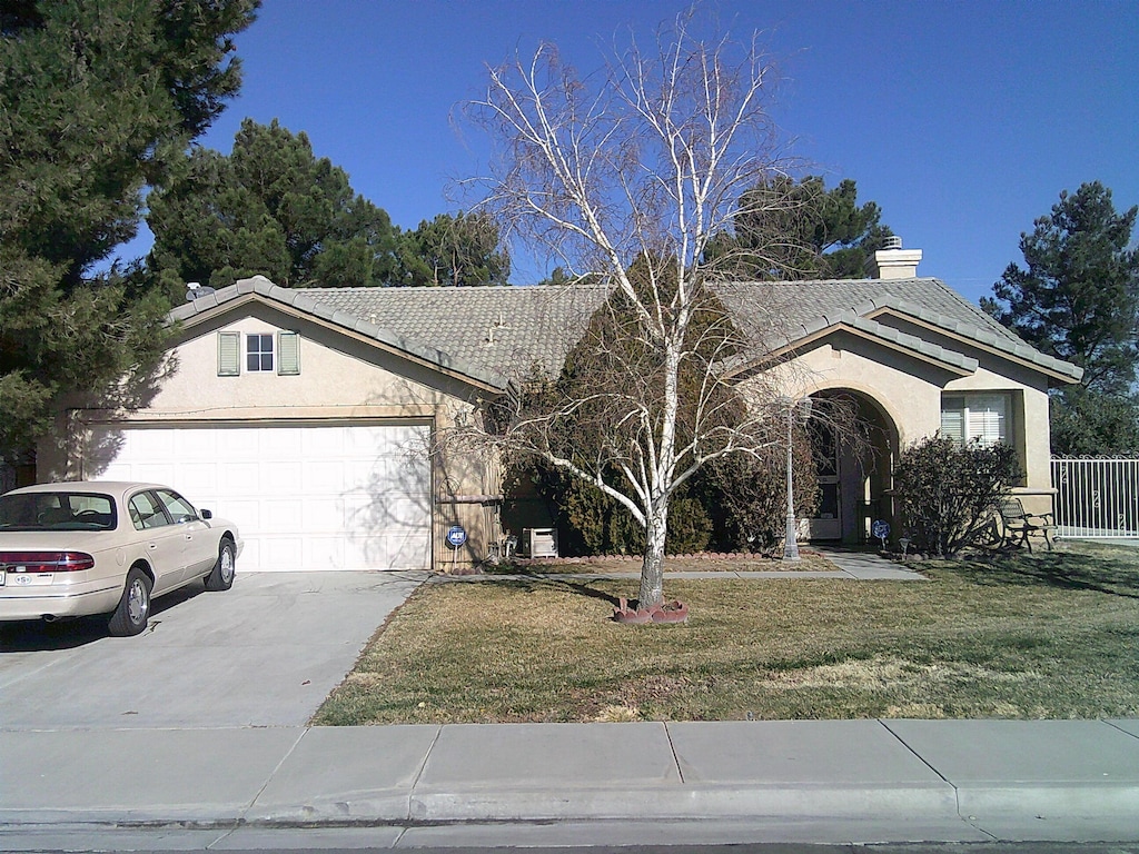 ranch-style house with a garage and a front lawn