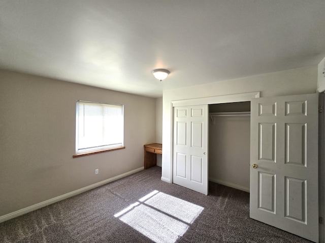 unfurnished bedroom featuring dark carpet and a closet