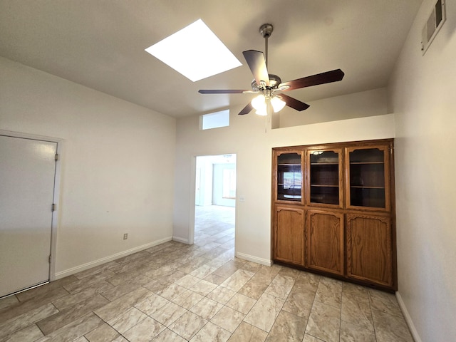 empty room featuring ceiling fan and a skylight