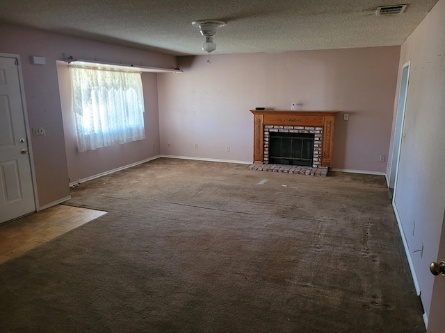 unfurnished living room with dark colored carpet, ceiling fan, a textured ceiling, and a brick fireplace