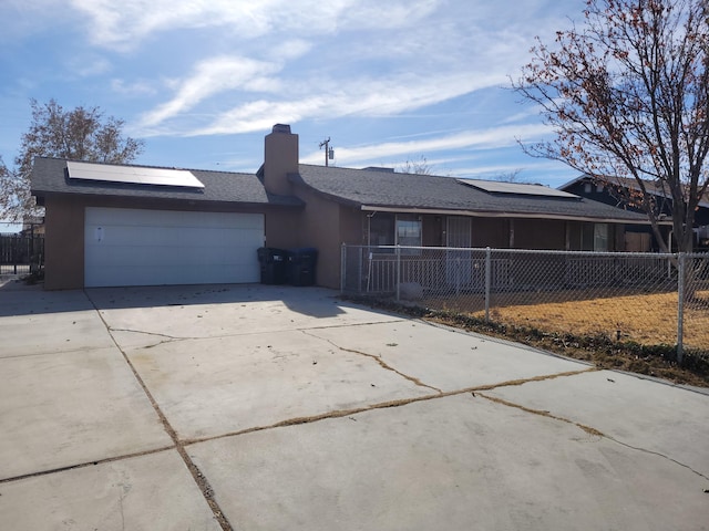 single story home featuring solar panels and a garage