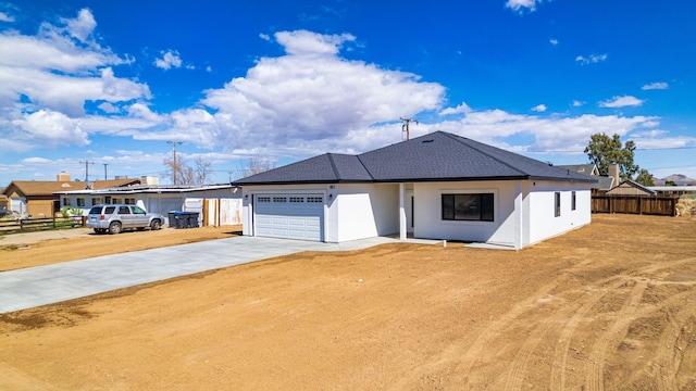 view of front of home with concrete driveway, an attached garage, fence, and stucco siding