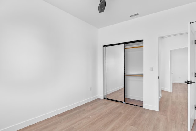 unfurnished bedroom featuring a closet, baseboards, visible vents, and light wood finished floors