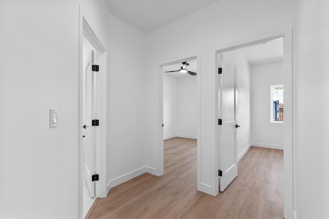 corridor featuring baseboards and light wood-type flooring