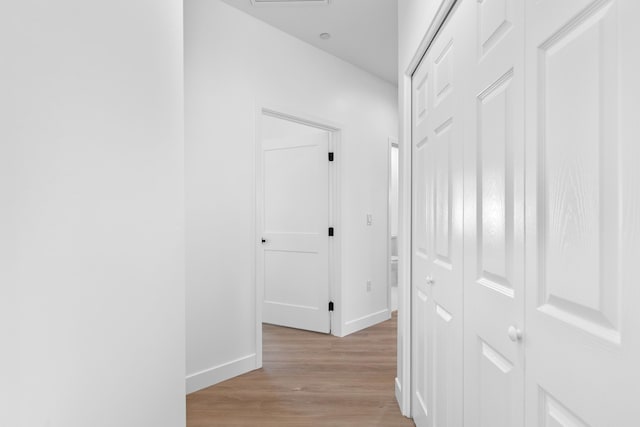 hallway featuring baseboards and light wood finished floors