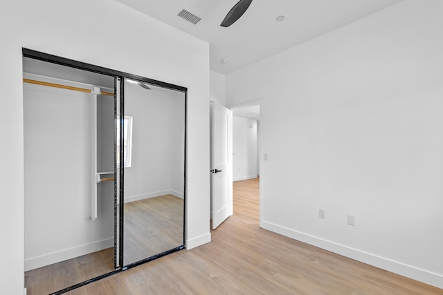 unfurnished bedroom featuring light wood-type flooring, visible vents, baseboards, and a closet