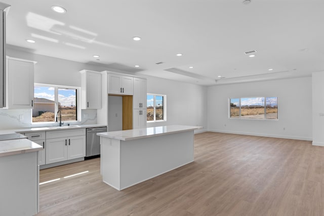 kitchen with tasteful backsplash, dishwasher, light wood-type flooring, a raised ceiling, and a sink