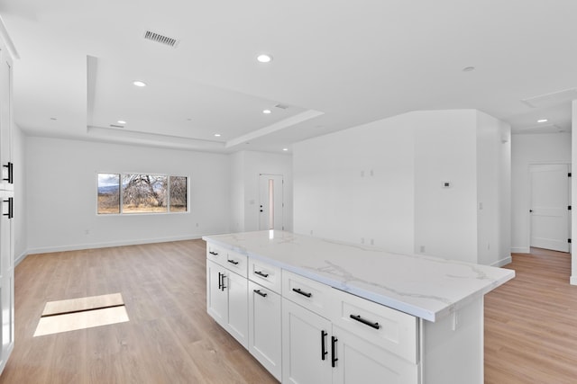 kitchen with visible vents, open floor plan, white cabinetry, light wood finished floors, and a raised ceiling
