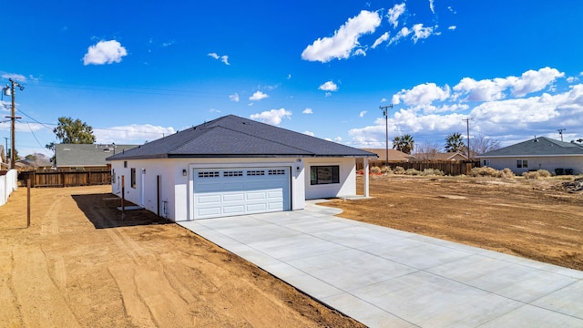 exterior space with a garage, concrete driveway, stucco siding, and fence