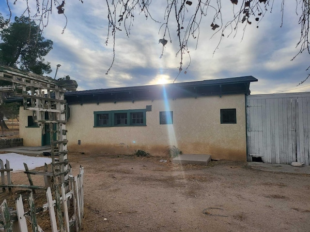 rear view of property featuring fence and stucco siding