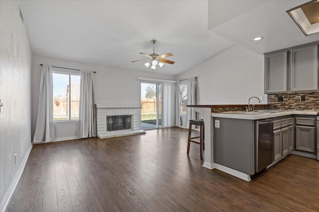 kitchen featuring gray cabinets, sink, backsplash, a kitchen breakfast bar, and kitchen peninsula