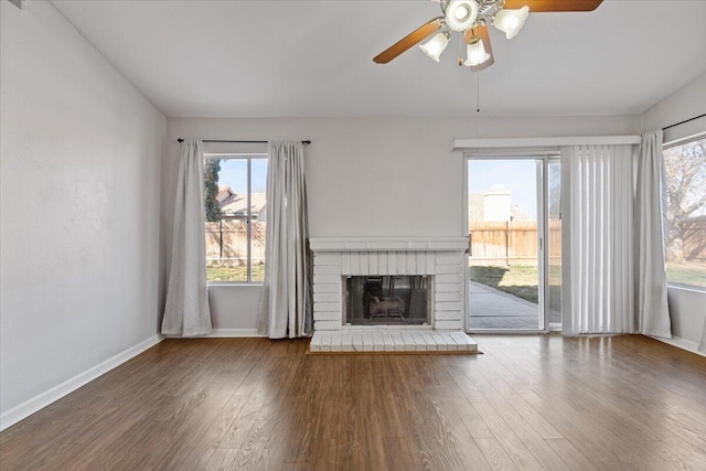 unfurnished living room with ceiling fan, dark hardwood / wood-style flooring, and a brick fireplace