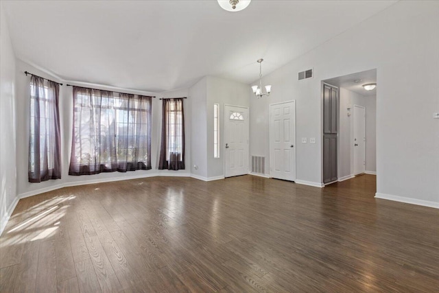 unfurnished living room featuring lofted ceiling, an inviting chandelier, and dark hardwood / wood-style flooring