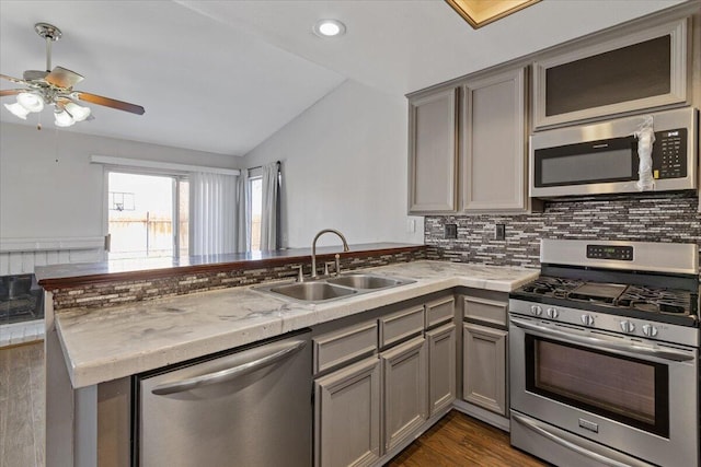 kitchen with appliances with stainless steel finishes, lofted ceiling, sink, gray cabinetry, and kitchen peninsula