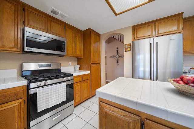 kitchen featuring appliances with stainless steel finishes, light tile patterned floors, and tile counters