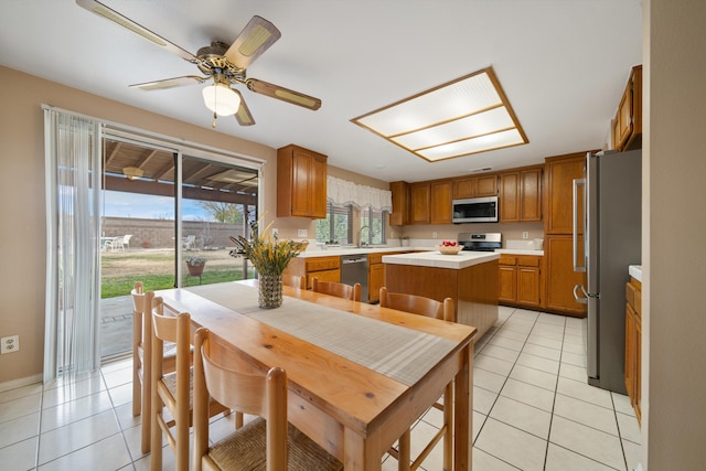 kitchen with ceiling fan, a center island, light tile patterned flooring, and stainless steel appliances