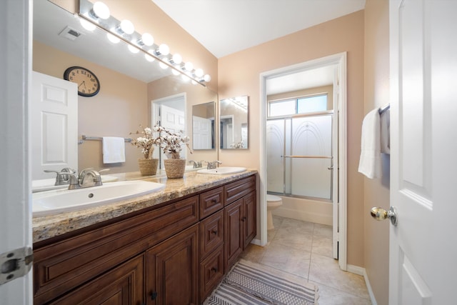 full bathroom with shower / bath combination with glass door, vanity, tile patterned flooring, and toilet