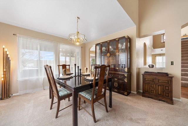 dining area featuring light carpet and a chandelier