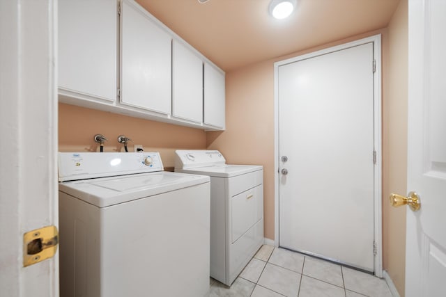 clothes washing area featuring washer and dryer, light tile patterned floors, and cabinets