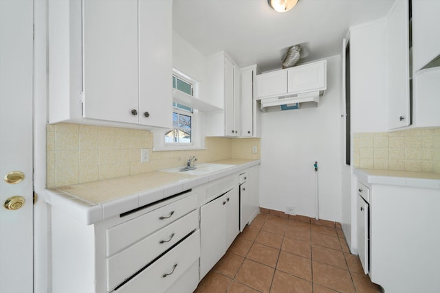 kitchen featuring tile counters, tasteful backsplash, tile patterned floors, white cabinets, and sink