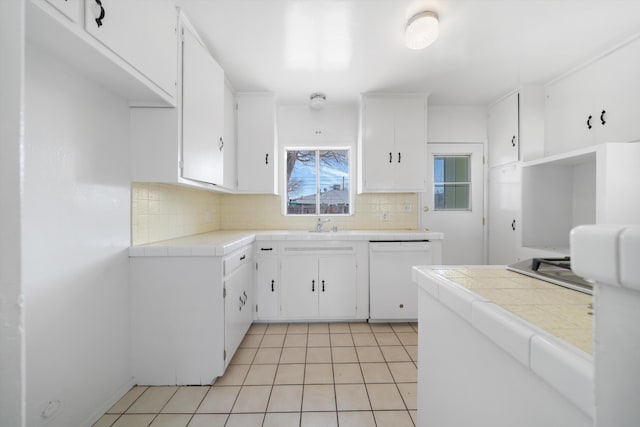 kitchen with white cabinets, dishwasher, light tile patterned floors, and tile countertops