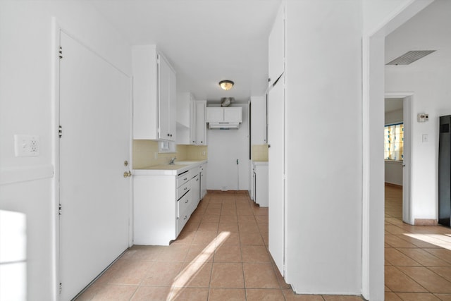 kitchen with sink, backsplash, light tile patterned flooring, and white cabinetry