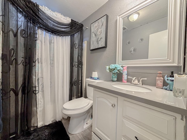 full bathroom featuring toilet, a textured ceiling, shower / tub combo, and vanity