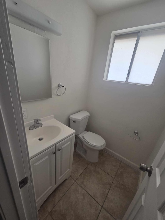 half bathroom with toilet, tile patterned floors, and vanity