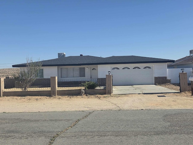 ranch-style house featuring an attached garage, a fenced front yard, and concrete driveway