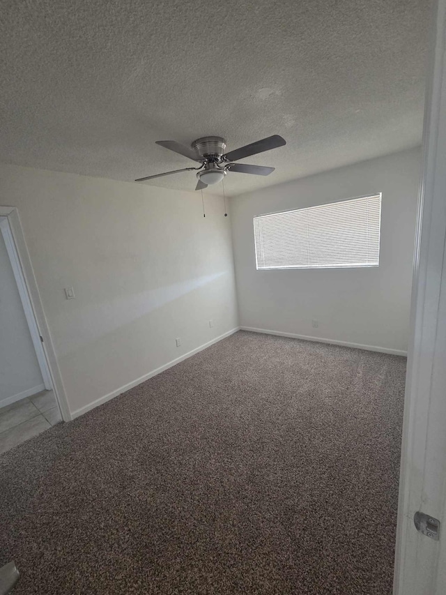 carpeted empty room featuring ceiling fan, a textured ceiling, and baseboards