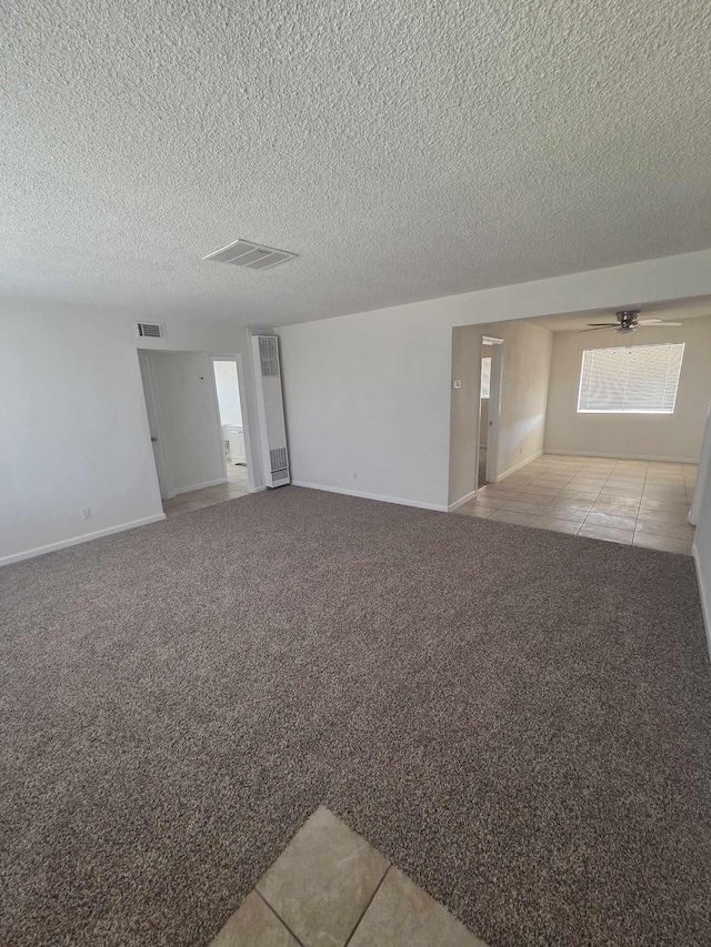 carpeted empty room with tile patterned flooring, baseboards, and a textured ceiling