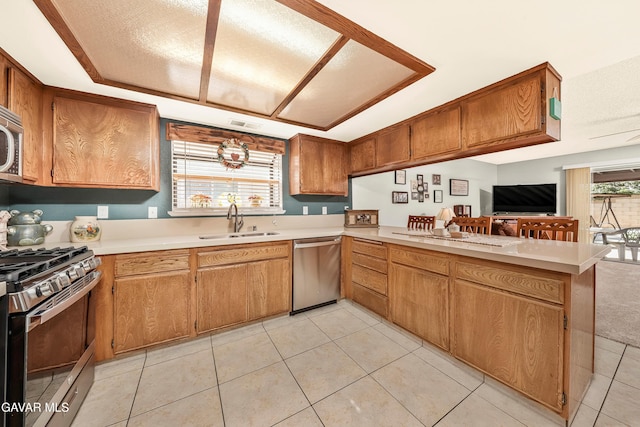 1037 Herzel Ave, Lancaster, CA 93535 - kitchen with appliances with stainless steel finishes, light countertops, a peninsula, light tile patterned floors, and brown cabinetry