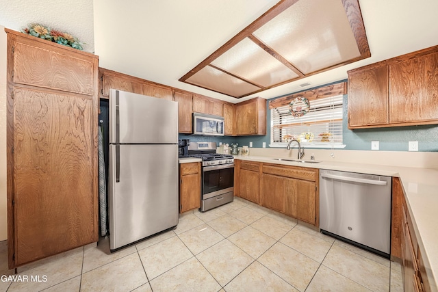 1037 Herzel Ave, Lancaster, CA 93535 - kitchen with stainless steel appliances, light countertops, light tile patterned floors, and brown cabinets