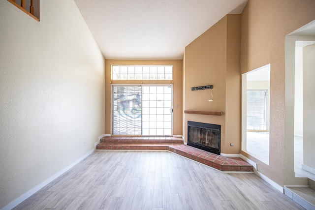 42443 Surrey Ct, Quartz Hill, CA 93536 - unfurnished living room with wood finished floors, a brick fireplace, baseboards, and a textured wall